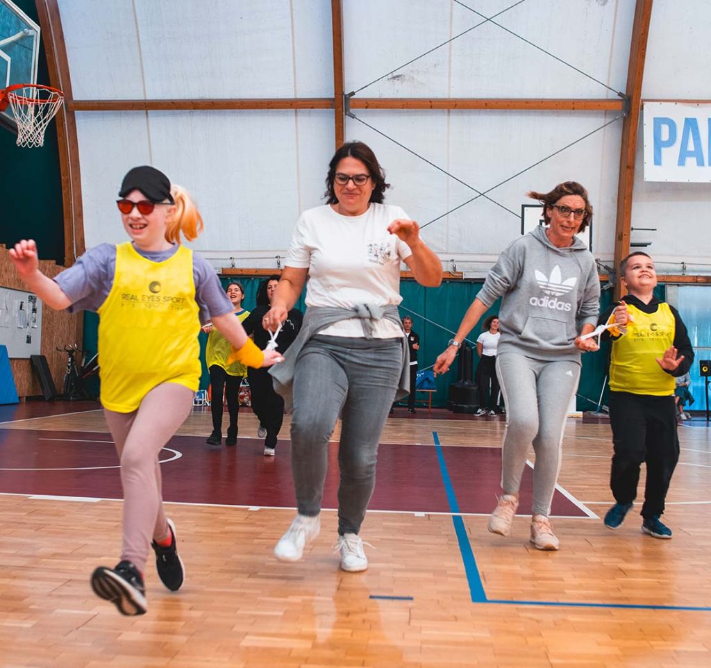 Ragazzi non vedenti aiutati da volontari dell'associazione REAL EYES SPORT ASD APS praticano attività fisica in palestra