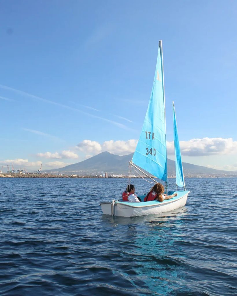 Barca a vela nel Golfo di Napoli, sullo sfondo il Vesuvio