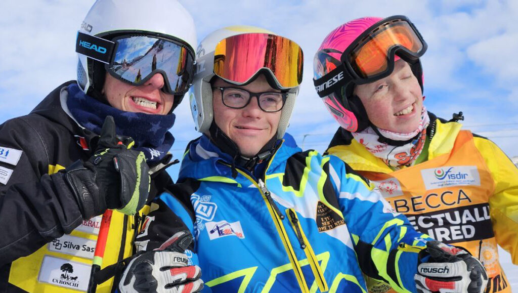 3 ragazzi in abbigliamento invernale con maschera e casco da sci